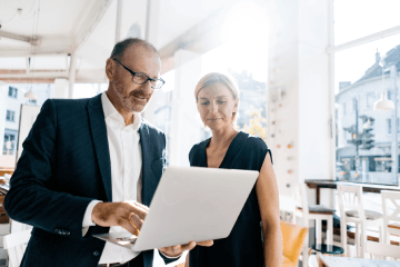 Man showing woman something on a laptop