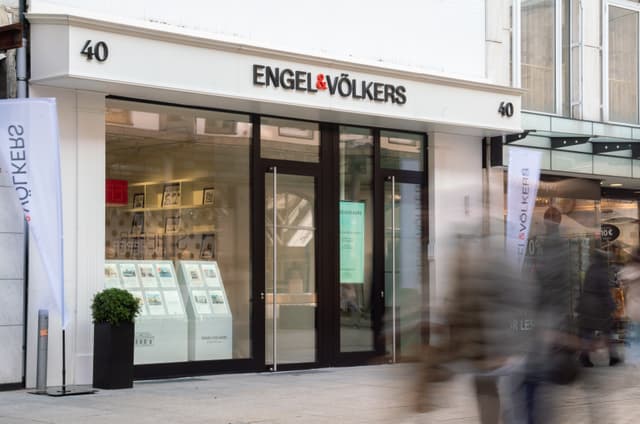 Engel & Völkers real estate office storefront with black framed windows and white signage.