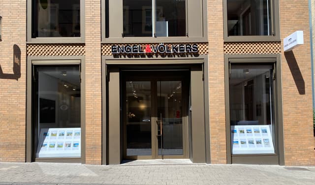 Engel & Völkers real estate office with a brick facade and large windows displaying property listings.