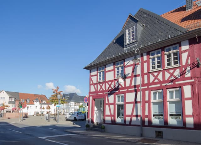 Engel & Völkers real estate office in a red and white half-timbered building on a sunny day.