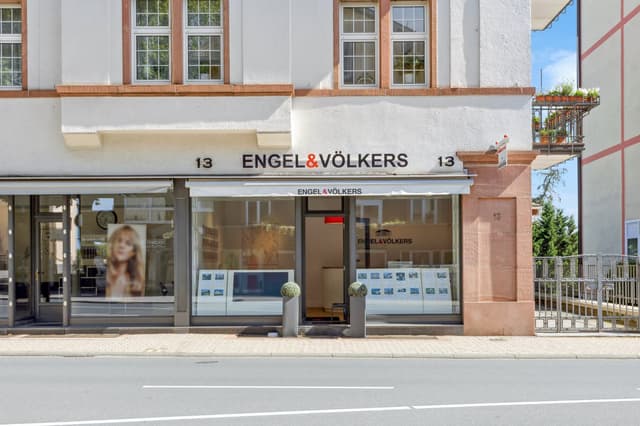 Engel & Völkers real estate office at street level. The building is white with brown trim and large windows.