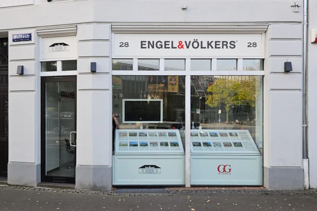 Exterior of Engel & Völkers real estate office with property listings displayed in the window.