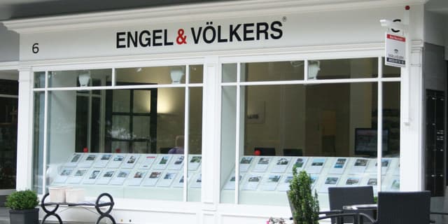 Engel & Völkers real estate office with white framed windows displaying property listings. A sign reads "Bad Nauheim".