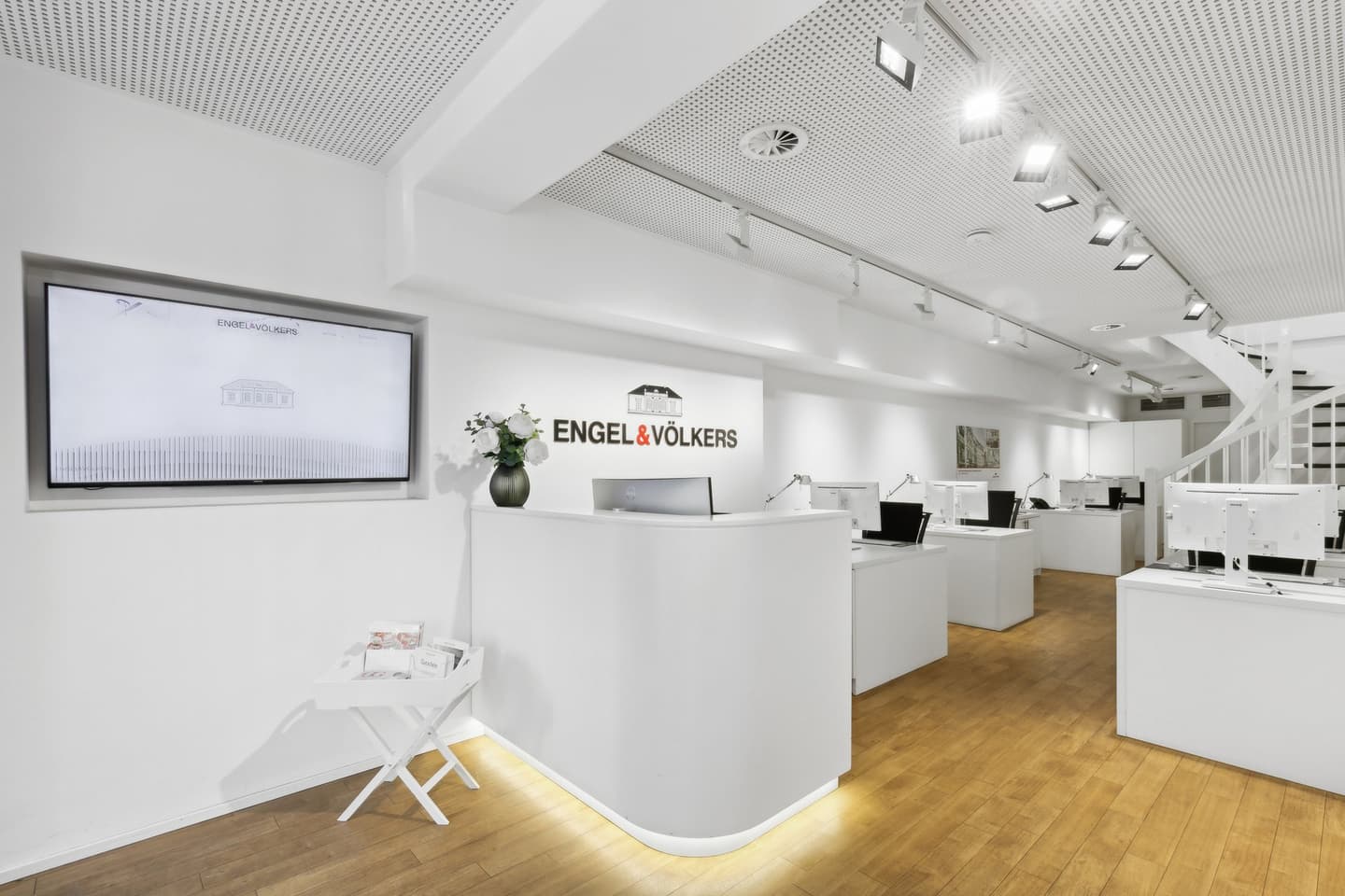 Engel & Völkers real estate office storefront with glass windows and black door frames on a stone building.