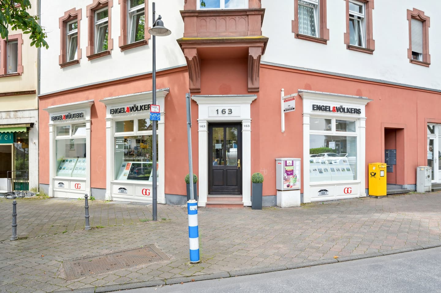 Engel & Völkers real estate office with two white-framed windows displaying property listings on a peach-colored building.